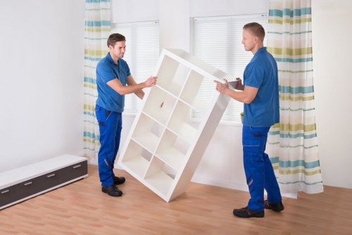 Removal workers carrying furniture down stairs in a Westminster property